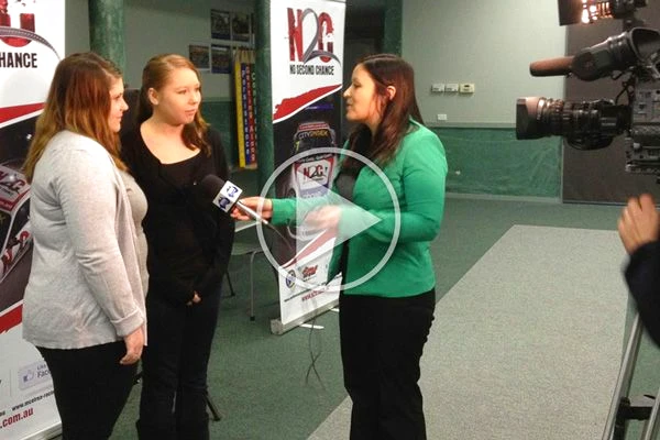 A WIN News reporter interviews two Benalla College students in a hall beside a television camera